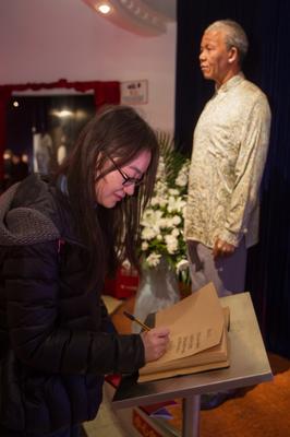 游客在上海杜莎夫人蠟像館曼德拉蠟像邊的吊唁本上寫下唁詞，寄托哀思